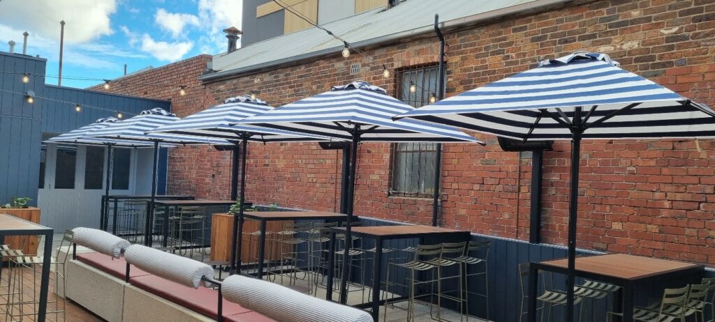 Row of white and black striped market umbrellas over outdoor tables